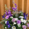 Purple and white floral arrangement with a clear glass cross centerpiece