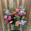 Tall mixed bouquet in a glass vase with pink, orange, and lavender flowers