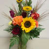 Mixed bouquet with sunflowers, roses, and carnations in a glass vase