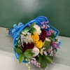 Bouquet of red, yellow, and white roses wrapped in blue paper