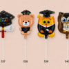 Four graduation-themed foil balloons shaped like a cap, bear, owl, and owl.