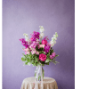 Pink and white flower arrangement in a clear glass vase on a draped table