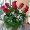 12 long stem red roses arranged in a tall glass vase with