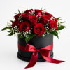 Red roses arranged in a black round box with a red ribbon