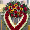 Heart-shaped floral wreath with red roses, white flowers, and yellow sunflowers