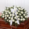 White rose casket spray with a white ribbon on a wooden casket