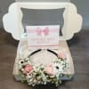 Pink roses and white daisies arranged in a gift box with a ribbon card