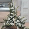 White floral basket arrangement with tall spikes and a white ribbon