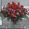 Red floral casket spray with greenery on a gray casket