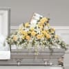Yellow and white floral casket spray on a gray casket