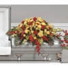 Red and yellow floral casket spray on a silver casket