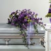 Purple floral casket spray with trailing ribbon