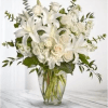 White lilies and roses arranged in a clear glass vase