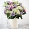 Lavender and white flowers arranged in a white vase