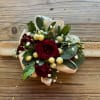Red rose bouquet with white berries and ribbon on a wooden surface