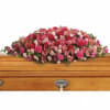 Pink and red floral casket spray on a wooden coffin