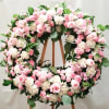 Large pink and white floral wreath on a wooden stand