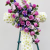 Cross-shaped floral spray with pink roses and white chrysanthemums on an easel