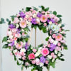 Heart-shaped floral wreath with pink, white, and purple flowers on an easel