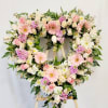 Heart-shaped floral wreath with pink and white flowers on an easel
