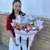 Woman holding a large pastel bouquet with lilies, roses, and blue hydrangeas