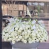 Large white rose arrangement in a gray container with white orchid stems