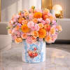 Pink and peach flower arrangement in a white box with apples