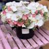 Pink and white floral arrangement in a black hat box