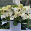 White and pale green floral arrangement in a white vase