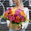 Bright mixed bouquet in a round box with pink, orange, and yellow flowers