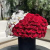 Large red rose arrangement with white orchids in a black vase