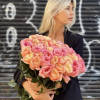Woman holding a large bouquet of pink and peach roses