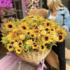 Large basket of yellow sunflowers and roses being held by a woman