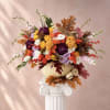 Colorful floral arrangement in a pumpkin vase with autumn leaves