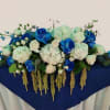 Blue and white floral arrangement with roses and hydrangeas on a draped table