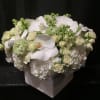 White floral arrangement in a square vase with orchids and roses