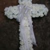 White floral cross with a ribbon bow and hanging memorial ribbons