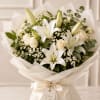 White lilies and roses arranged in a wrapped bouquet with cream ribbon.