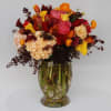 A vase filled with hydrangeas, coral peonies, gold, orange, burgundy calla lilies