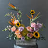 Tropical floral arrangement with sunflowers, roses, and bird of paradise in a wooden box
