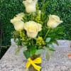 White roses in a glass vase with a yellow ribbon