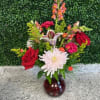 Mixed bouquet with red roses, a white daisy, and lilies in a glass vase
