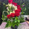 Red and white roses arranged in a black vase with greenery