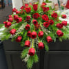 Cascade of red roses with evergreen accents on a dark table