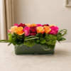 Mixed roses in a low rectangular glass vase with green accents