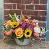 Mixed bouquet in a white bowl vase with sunflowers, roses, hydrangea, and tulips