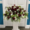 Large burgundy and white floral arrangement on a white pedestal