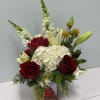 Red roses and white hydrangea in a square vase with lilies and snapdragons