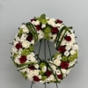 Circular wreath of red, white, and green flowers on a stand