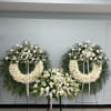 Three white floral funeral wreaths and sprays on stands